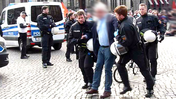 Freund und Helfer: Polizei schleppt herumstehenden Protestierer vom Marktplatz.